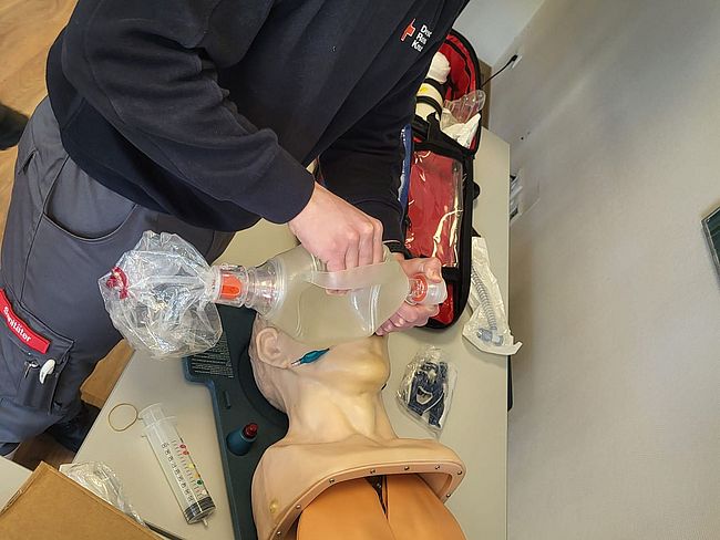 Ein Helfer übt die Intubation an einer Puppe
