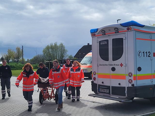 Helfer schieben einen Patienten auf einem mobilen Tragegestell