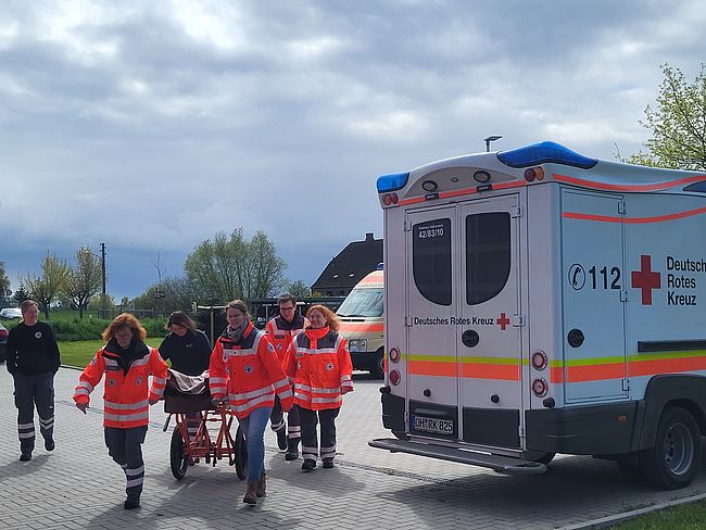 Helfer schieben einen Patienten auf einem mobilen Tragegestell