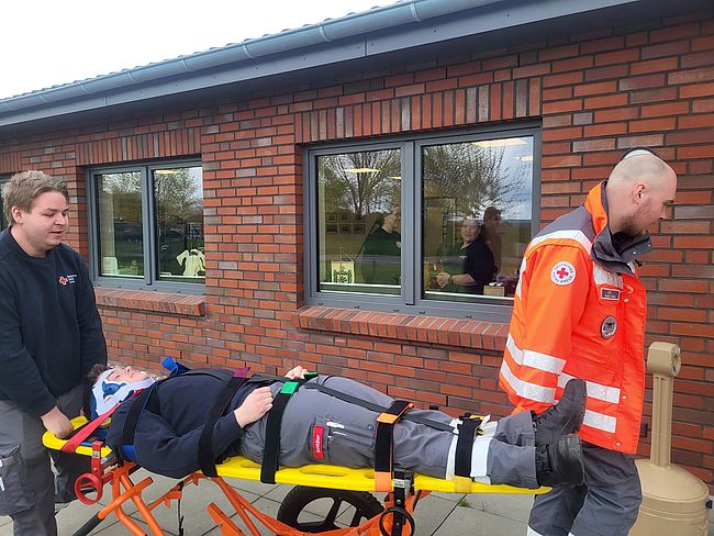 Helfer schieben einen Patienten auf einem Spineboard mit Tragegestell