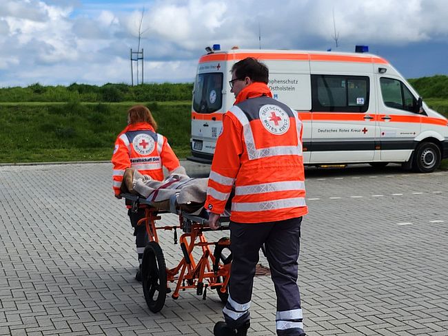 Helfer schieben einen Patienten auf einem Tragegestell