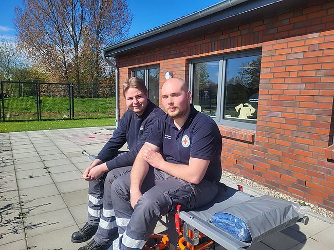 2 Helfer sitzen in der Übungspause auf einer Trage